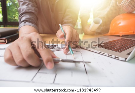 Hands of architect or engineer using pencil with blueprint on desk in office.Team of architects engineer discussing and check documents and business workflow.Construction concept.