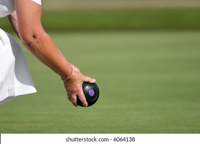 Hands and arm of a female holding a lawn bowling ball about to bowl.