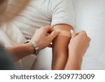 Hands, arm and woman with bandage for kid in home bedroom for wellness or healthcare. Family, first aid and mother apply bandaid plaster on hurt or injured child for injury or medical injection