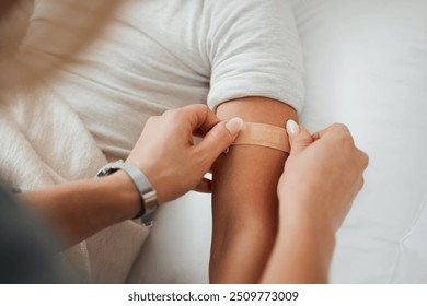 Hands, arm and woman with bandage for kid in home bedroom for wellness or healthcare. Family, first aid and mother apply bandaid plaster on hurt or injured child for injury or medical injection