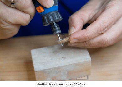 Hands of Artisan Woman Making a Hole in a Stone to Make Jewelry with a Rotary Tool - Powered by Shutterstock