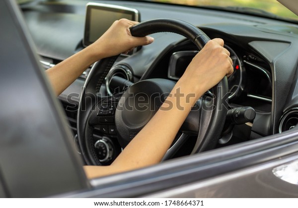 The hands of an Asian tourist woman\
driving a private car using both hands to hold the steering wheel\
for travel, learn to drive a car, test drive a\
car