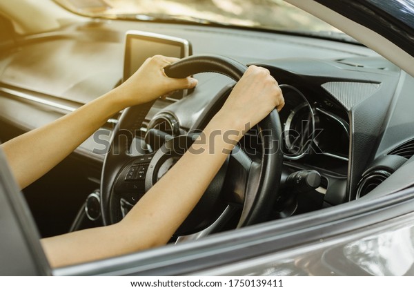 The hands of an Asian tourist woman\
driving a private car using both hands to hold the steering wheel\
for travel, learn to drive a car, test drive a\
car