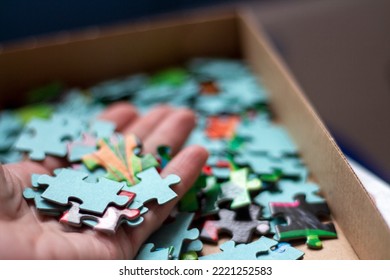 Hands assembling jigsaw puzzle, put pieces together searching for right match, top close up view
