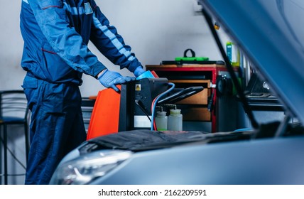 Hands of auto mechanic include the installation of refilling the air conditioner in car service