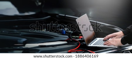Hands of auto mechanic using computer for diagnostics engine working and repairing car in a garage. Blur repair service in background. wide panoramatic banner with empty space for copy text.