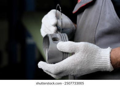 The hands of an auto mechanic who holds the engine piston and the ring. Close-up. Before installing the piston, a specialist checks the serviceability of the piston ring grooves. - Powered by Shutterstock