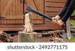 Hands and axe in firewood, man chopping wood for fire heat, preparing firewood for winter in summer season