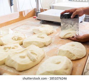 Hands Of Baker Portioning Raw Dough With Scraper Before Shaping Bread..