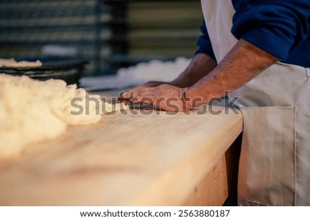 The hands of a baker shape the flour dough to then make bread.	