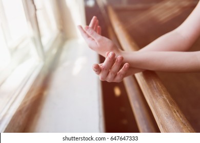 Hands of a ballerina close-up on ballet barre.