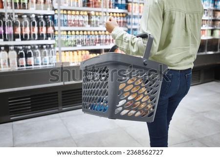 Hands, basket and customer grocery shopping for drink at store, supermarket and mall for food. Groceries, soda market and person in retail shop for choice of product, sales deal and discount on juice