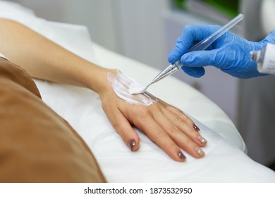 Hands Of A Beautician Doctor Apply Anesthetic Cream To The Patient's Hands