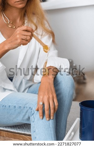 The hands of the beautician hold liquid sugar paste or wax for the duration of the depilation procedure in the salon. Close up, background image