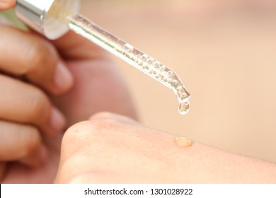 Hände einer schönen Frau Dropping Serum Collagen Feuchtigkeitscreme aus Gesicht in Hand weiche helle Hintergrund. Protektorhaut Behandlung Gesichtsöl, Vitamin C. Schönheit und Spa Konzept