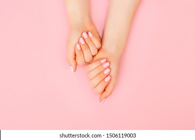 Hands of a beautiful woman on a pink background. Delicate hands with natural manicure, clean skin. Light pink nails.