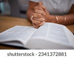 Hands, bible and woman in prayer in home and learning or reading about Jesus or faith, religion and worship for mindfulness. Person, praying and studying holy book for peace, praise and meditation