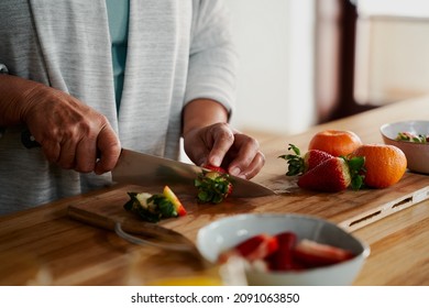 Hands of biracial elderly female chopping strawberries in modern kitchen. Preparing healthy meal for breakfast.  - Powered by Shutterstock