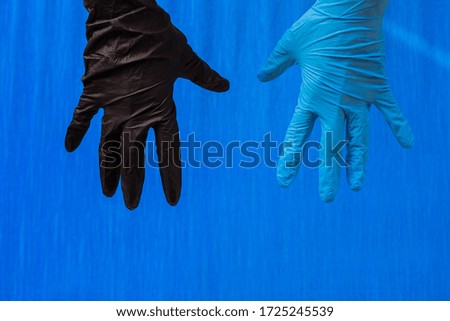 Hands up black and blue rubber medical gloves closeup. Isolated on blue background. Place for text. Copy space.
