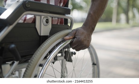 Hands Of Black Man Pushing Wheel Of Wheelchair, Life With Disability In A City