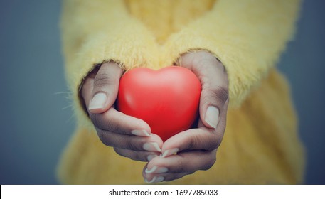 Hands Of A Black Woman Holding And Offering A Heart Shape. Love, Health Concept. Selective Focus.Cinematic Effect.