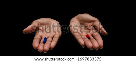 Hands of a black woman offering the red and the blue pills on a black background.  Concept of ugly truth vs beautiful lie, reality vs fiction.