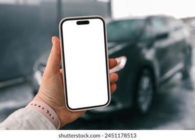 Hands with a blank phone screen on the background of a car wash. - Powered by Shutterstock