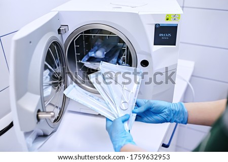 Hands in blue gloves holding a medical instrument. Sterilizing box. Sterilization of instruments. Dentist tools. Sterilization procedure. Steam autoclave. 
