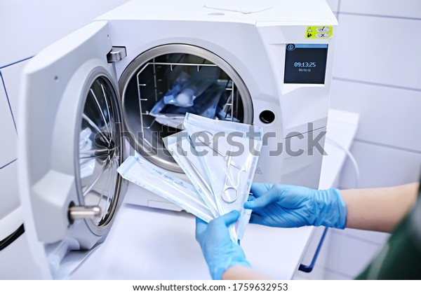Hands in blue gloves holding\
a medical instrument. Sterilizing box. Sterilization of\
instruments. Dentist tools. Sterilization procedure. Steam\
autoclave. 