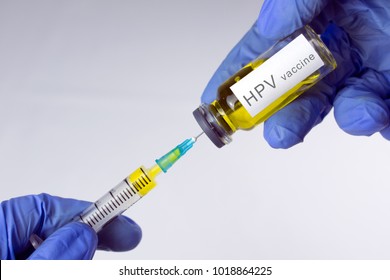 Hands in blue gloves are typing a yellow vaccine in a syringe. HPV vaccination concept. close-up, selective focus