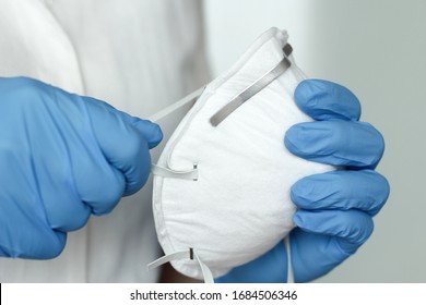 Hands with blue protective nitride gloves holding  N95, FFP2 respirator, face mask. Coronavirus, COVID-19 concept. Selective focus. - Powered by Shutterstock