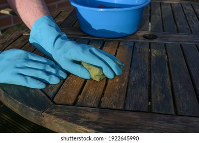 Hands in blue rubber gloves cleaning a weathered wooden garden table at the beginning of spring forthe outdoor season, copy space, selected focus - Powered by Shutterstock