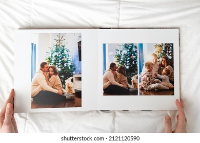 Hands With Book With New Year Photos Of Big Family At Home On A White Background. Photobook Is Gift. Professional Photographer And Designer. Printing Of Photos And Journals In Photo Laboratory