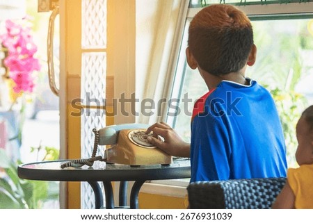 Hands of boy try to using old phone or dial telephone. Boy curious and tried using old rotary phone or dial phone. Curious child play with antique vintage rotary old landline phone. Old fashioned.
