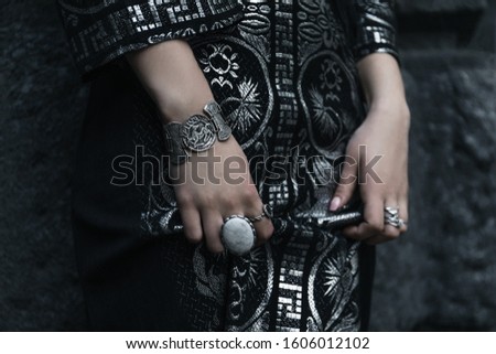 hands with bracelets and rings and a gothic black dress