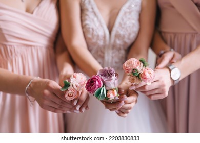 the hands of the bride and bridesmaids hold boutonnieres for the men before the ceremony.