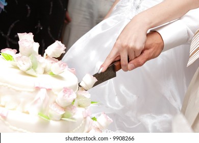 Hands Of Bride And Groom Cut Of A Slice Of A Wedding Cake