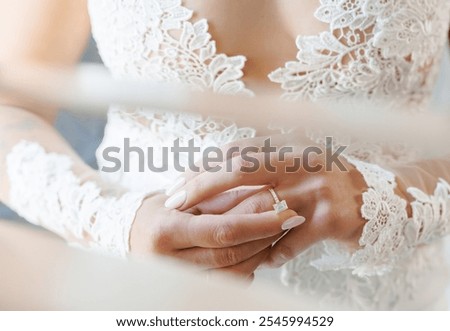 Hands of the bride with a wedding ring on her finger. Close-up of a bride in a white lace wedding dress gently touching her finger with a diamond engagement ring on her hand. Marriage and vows.