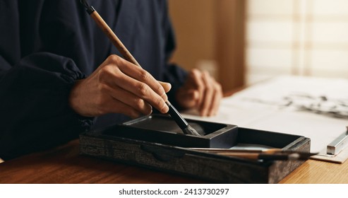 Hands, brush in ink for writing and Japanese calligraphy or ancient script for art and inkstone. Asian creativity, black paint and vintage tools, paintbrush and person with traditional stationery - Powered by Shutterstock