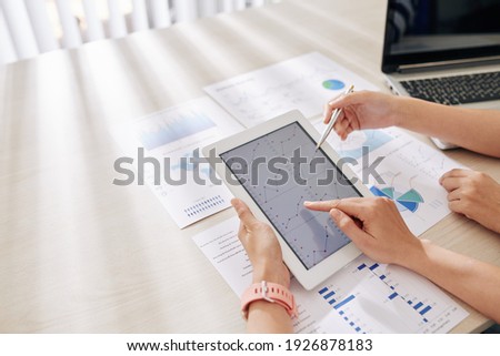 Hands of business people pointing at chart on tablet computer when working on financial strategy
