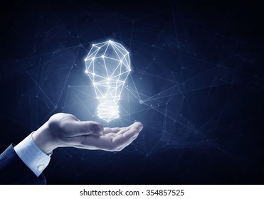 Hands of business person holding illuminated light bulb sign 
