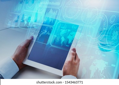 Hands of businessman with tablet computer at blurry table in office with double exposure of HUD business interface. Concept of data visualisation and hi tech. Toned image