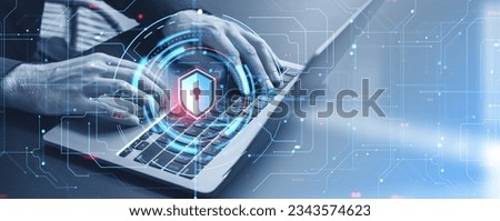 Hands of businessman typing on laptop keyboard at office table with double exposure of cyber security shield HUD interface. Concept of data leakage prevention and privacy in cyberspace