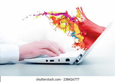 Hands of businessman using laptop and colorful splashes on screen
