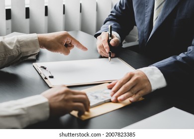 Hands of businessmen agreeing to the offer of bribery by signing a personal benefit agreement The concept of fraud and business practices within the company - Shutterstock ID 2007823385