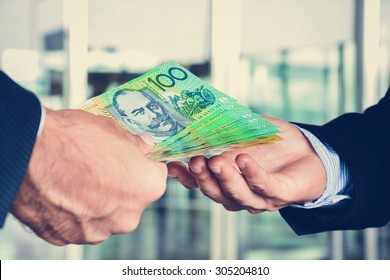 Hands of businessmen passing money, Australia dollar (AUD) banknotes