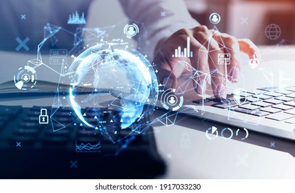 Hands of businesswoman with laptop at blurry table with double exposure of blue globe hologram. Concept of internet and global network connection. Toned image.