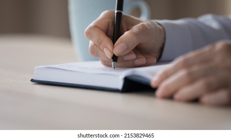 Hands of businesswoman writing notes in notebook close up. Employee scheduling project tasks, planning work, using agenda. Student, writer writing draft of essay, article
