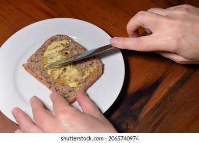 Hands Buttering Wholegrain Toast On A White Plate