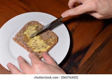 Hands Buttering Wholegrain Toast On A White Plate